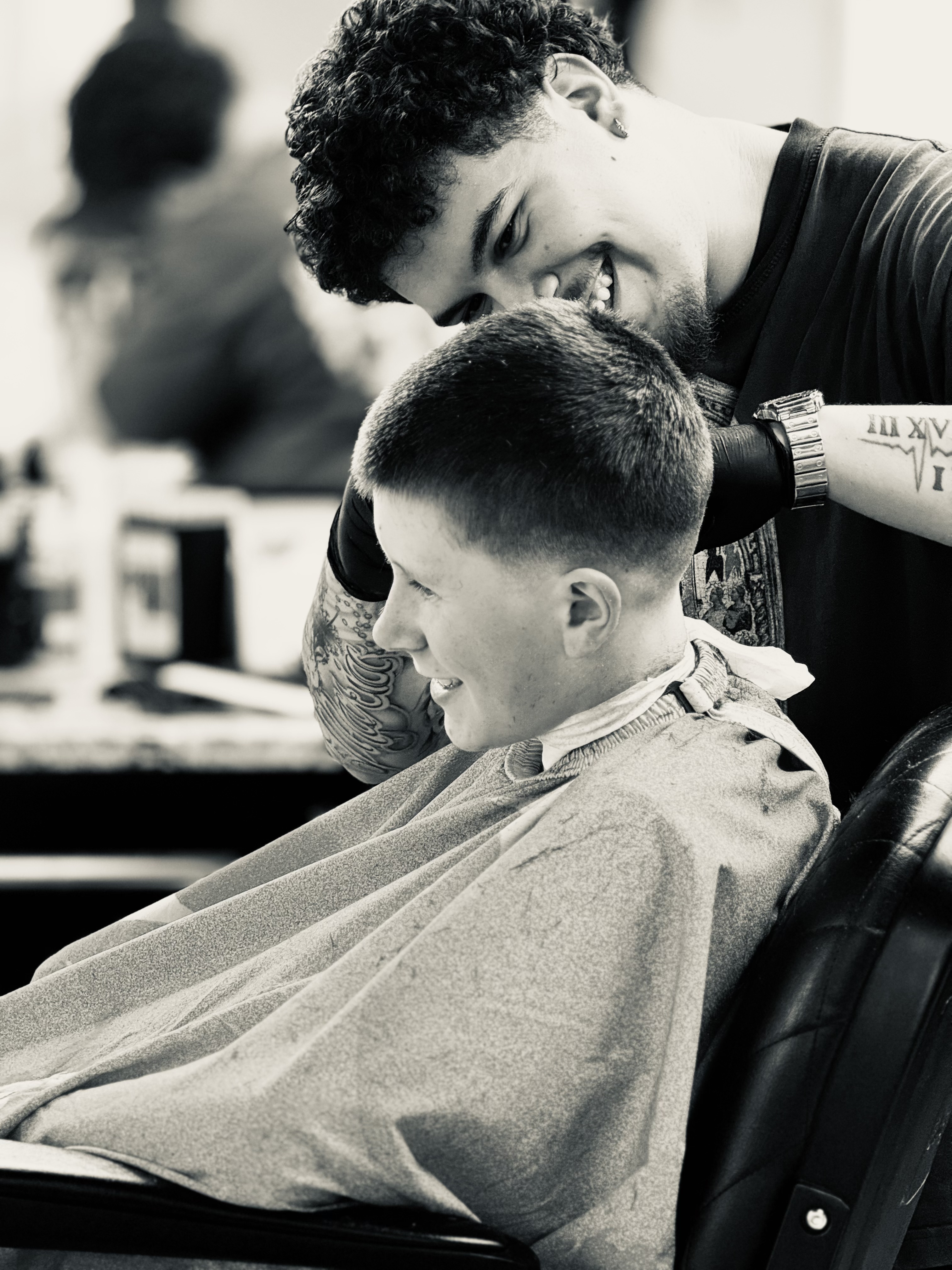 Barber cutting a young client's hair with both smiling